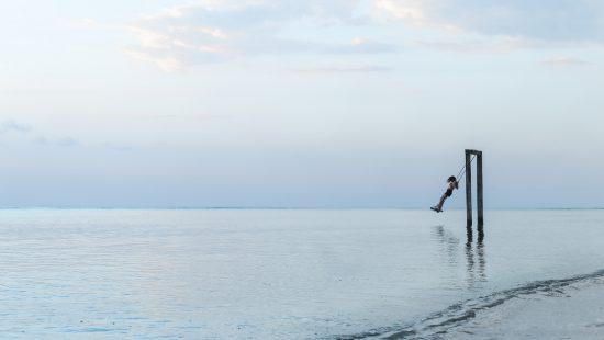 girls swinging over water